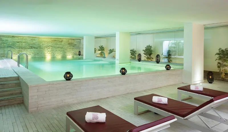 Espace de relaxation avec piscine intérieure et chaises longues.