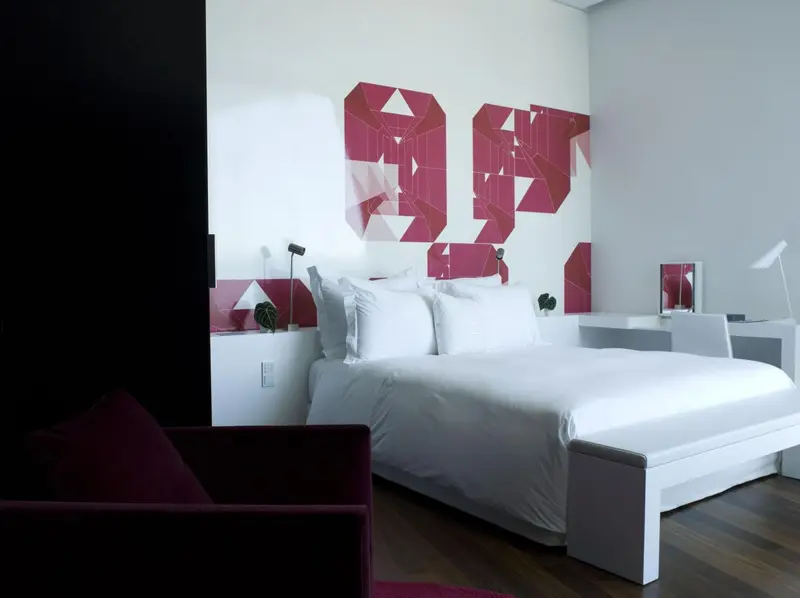 Une chambre lumineuse avec un grand lit recouvert de linge blanc.