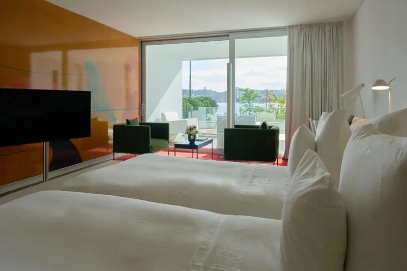 Chambre lumineuse avec un grand lit et une vue sur la mer.