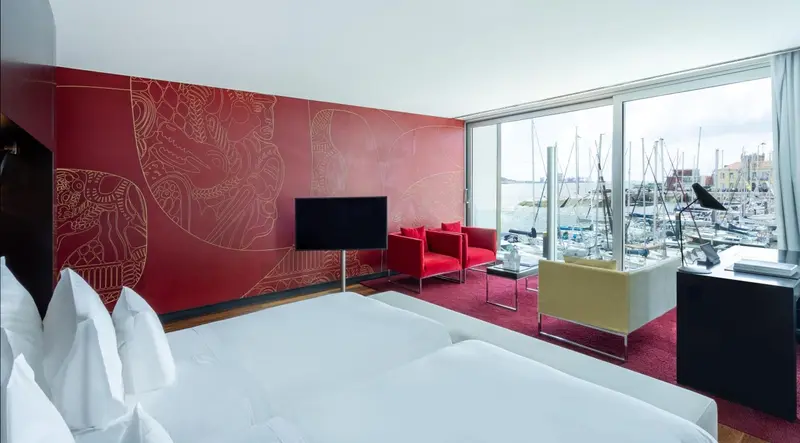 Chambre moderne avec un grand lit blanc et une vue sur un port de plaisance.