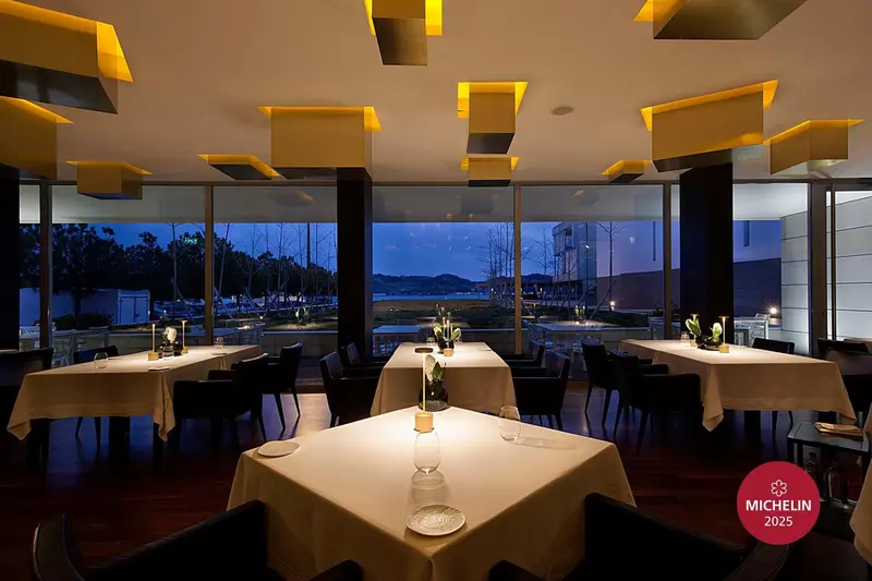 Une salle de restaurant élégante avec de grandes fenêtres donnant sur un paysage côtier.