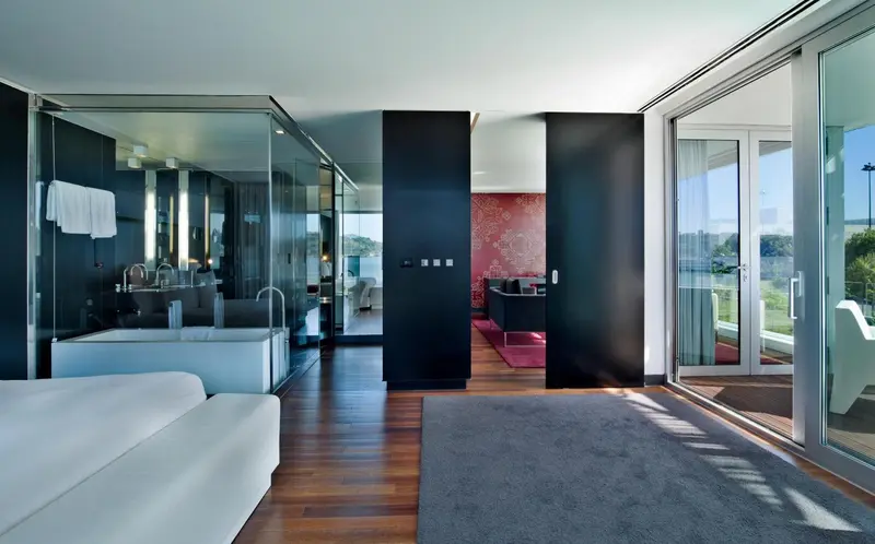 Une chambre moderne avec un canapé blanc et un accès à une terrasse ensoleillée.