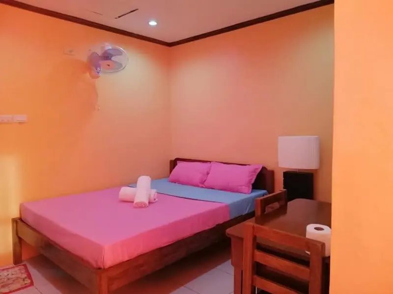 Une chambre lumineuse avec un lit recouvert d'un couvre-lit rose et d'un oreiller.