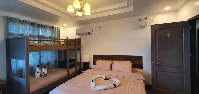 Une chambre avec un lit superposé et un lit double est décorée de rideaux et d'une lampe.