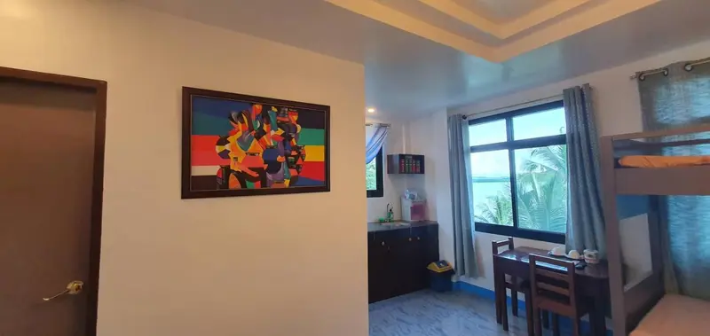 Une pièce lumineuse avec un tableau coloré au mur et un coin repas près d'une fenêtre.