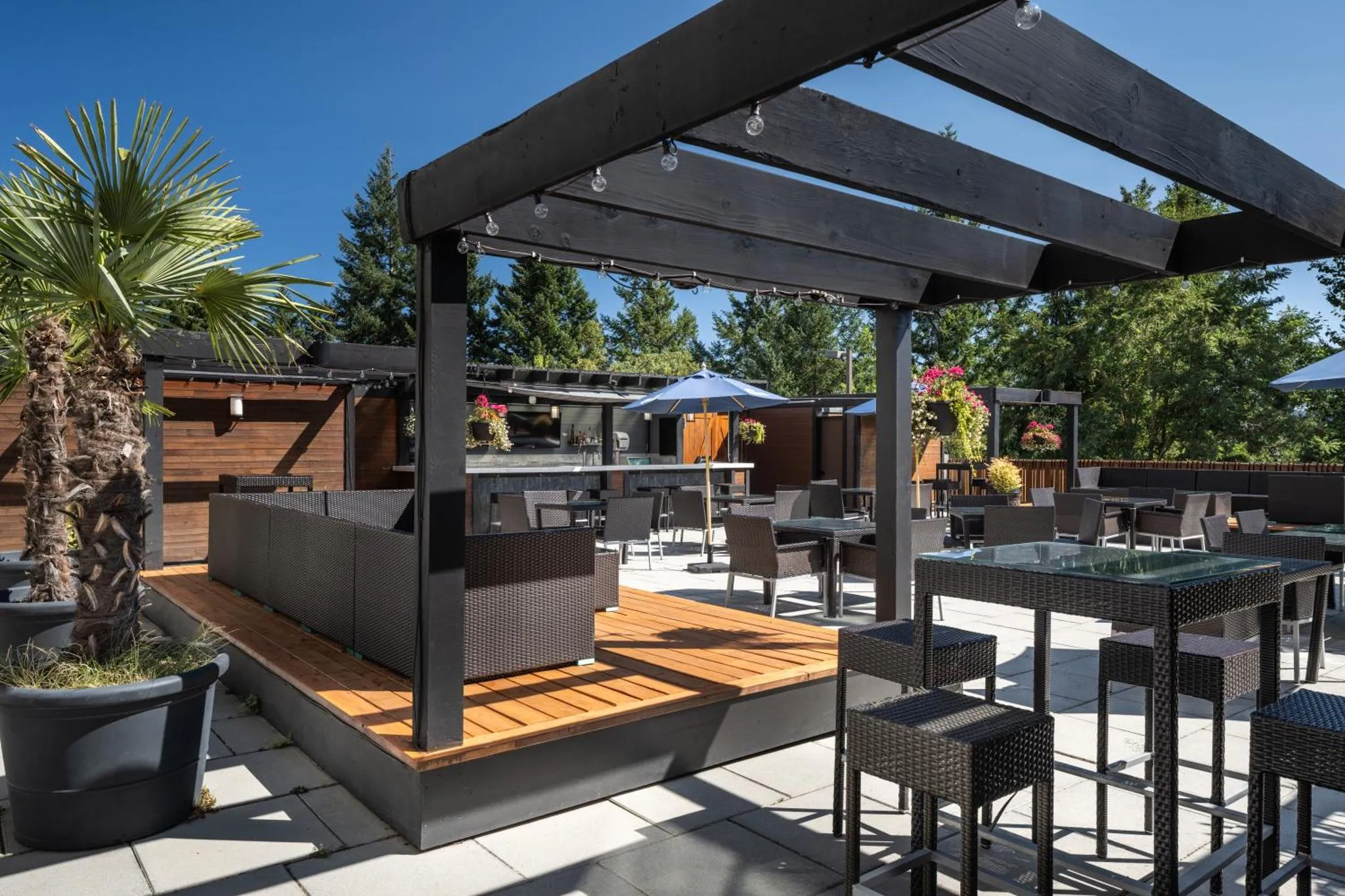 Terrasse ombragée avec mobilier de jardin et végétation tropicale.