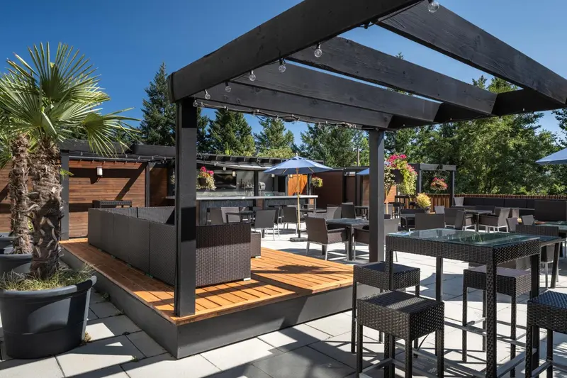 Terrasse ombragée avec mobilier de jardin et végétation tropicale.