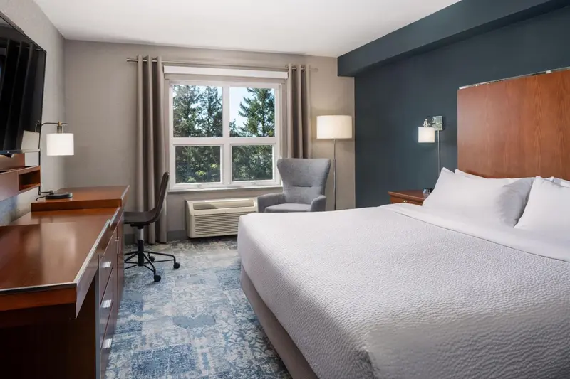 Une chambre d'hôtel lumineuse avec un lit double et un bureau.