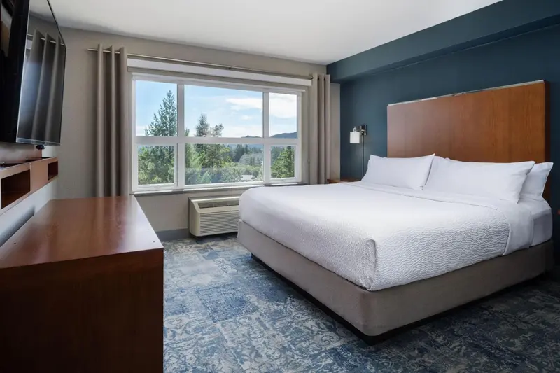 Une chambre lumineuse avec un grand lit et une vue sur la verdure.