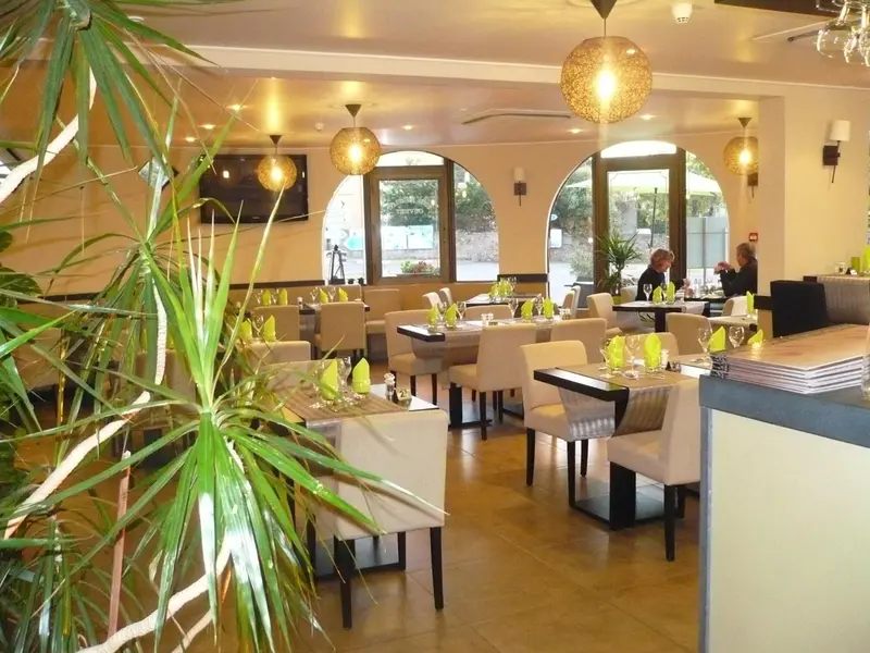 Une salle lumineuse avec des tables dressées pour un repas.