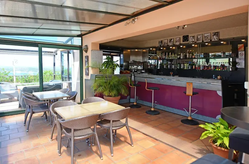 Un espace bar lumineux avec des tables et des chaises en terrasse.