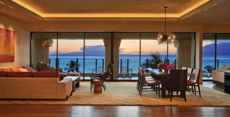 Un espace de vie lumineux s'ouvre sur une vue sur la mer au coucher du soleil.