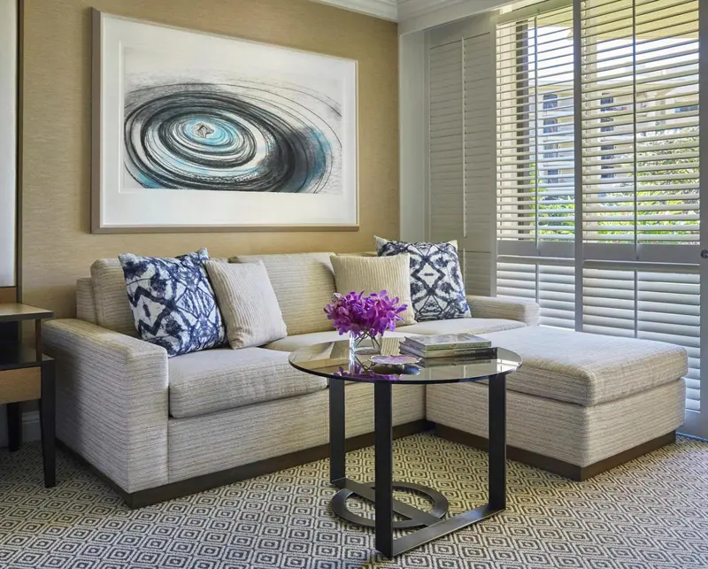 Un canapé et une table basse dans une pièce décorée avec un tableau abstrait.