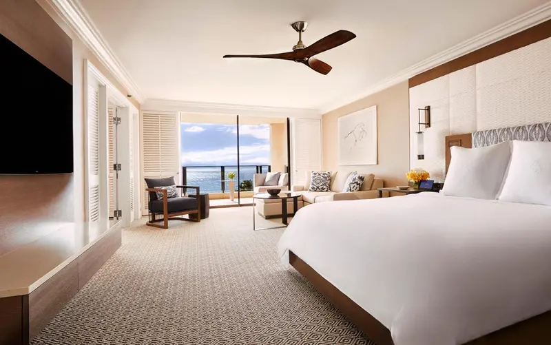 Une chambre lumineuse avec un grand lit et un coin salon donnant sur l'océan.