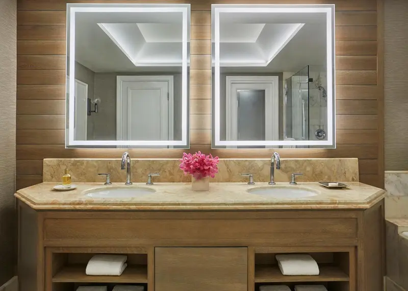 Une salle de bain lumineuse avec deux vasques et des miroirs.