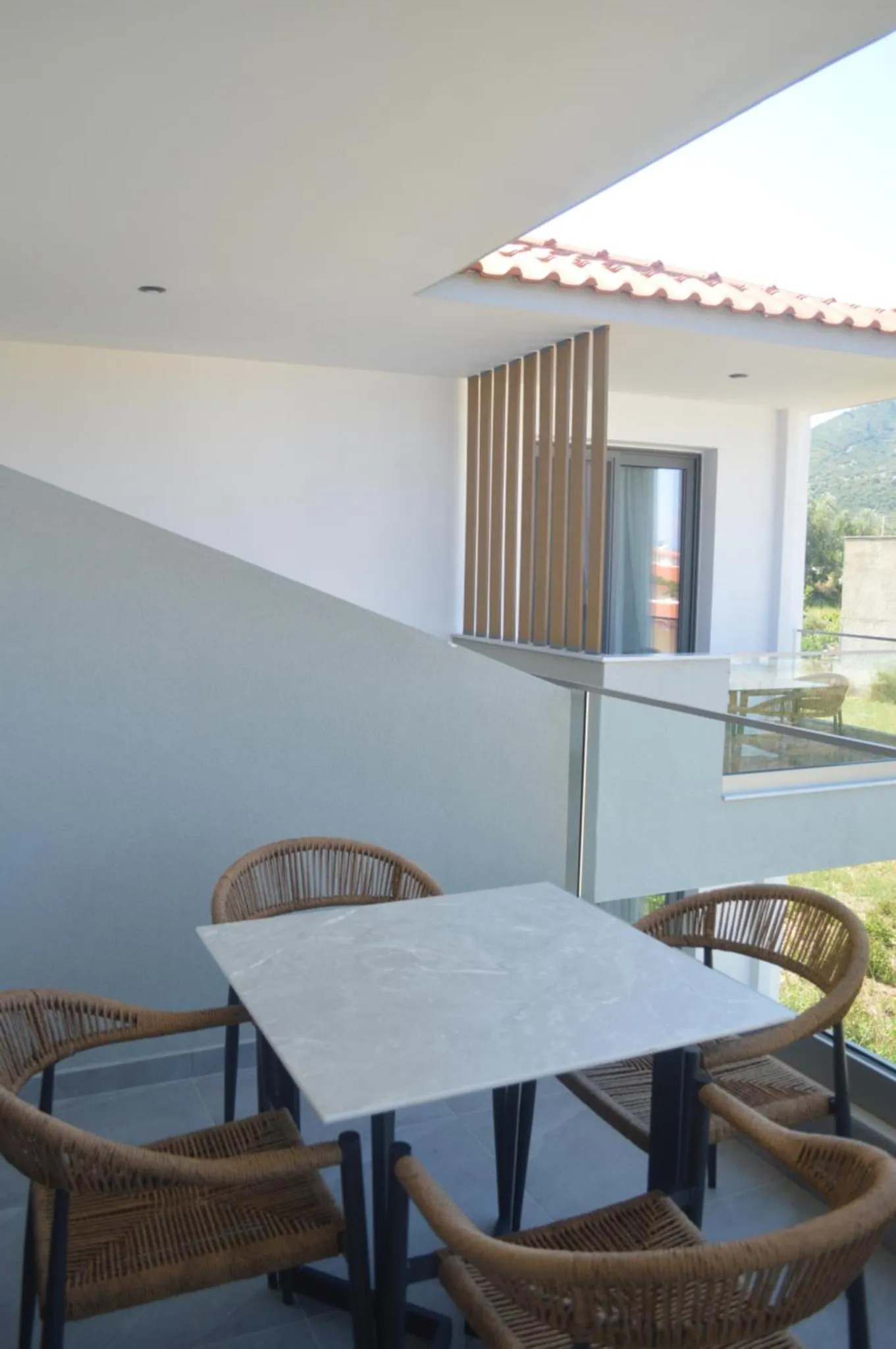Une table et des chaises en osier composent un espace repas sur une terrasse.