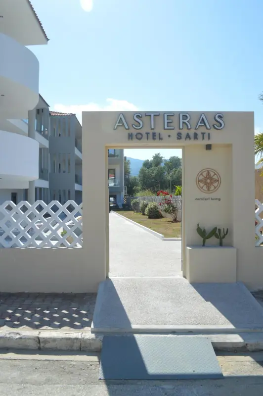 Entree d'un hotel avec une arche et un jardin soigné.
