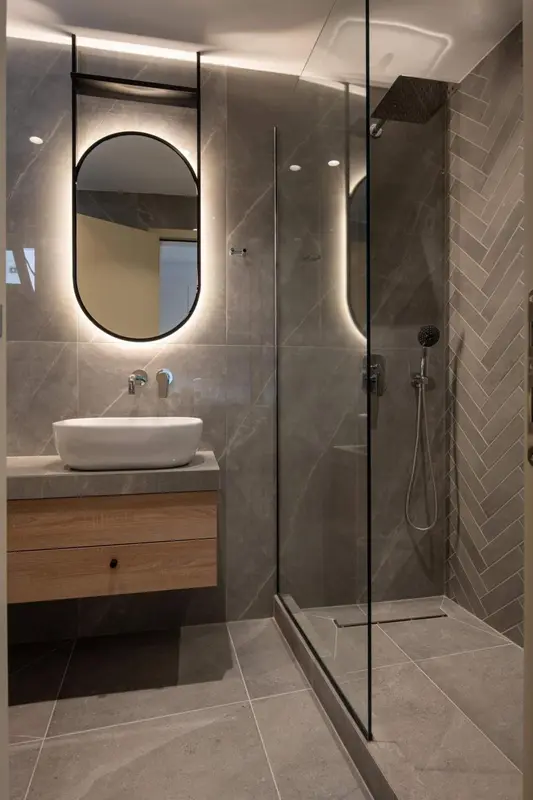 Une salle de bain moderne avec une douche à l'italienne et un grand miroir.