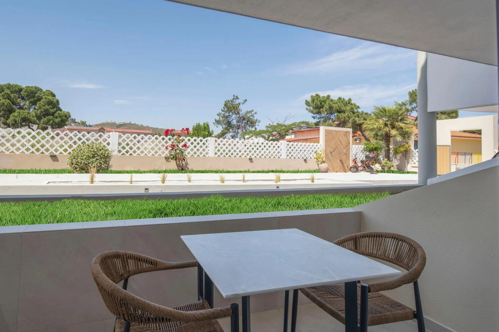 Une table et deux chaises en osier se trouvent sur une terrasse ensoleillée.