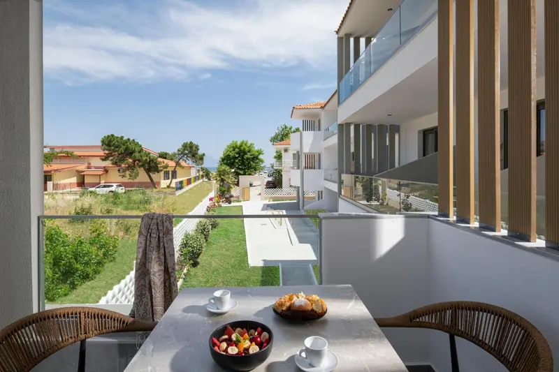 Une table avec des pâtisseries et des fruits est mise en scène sur un balcon.