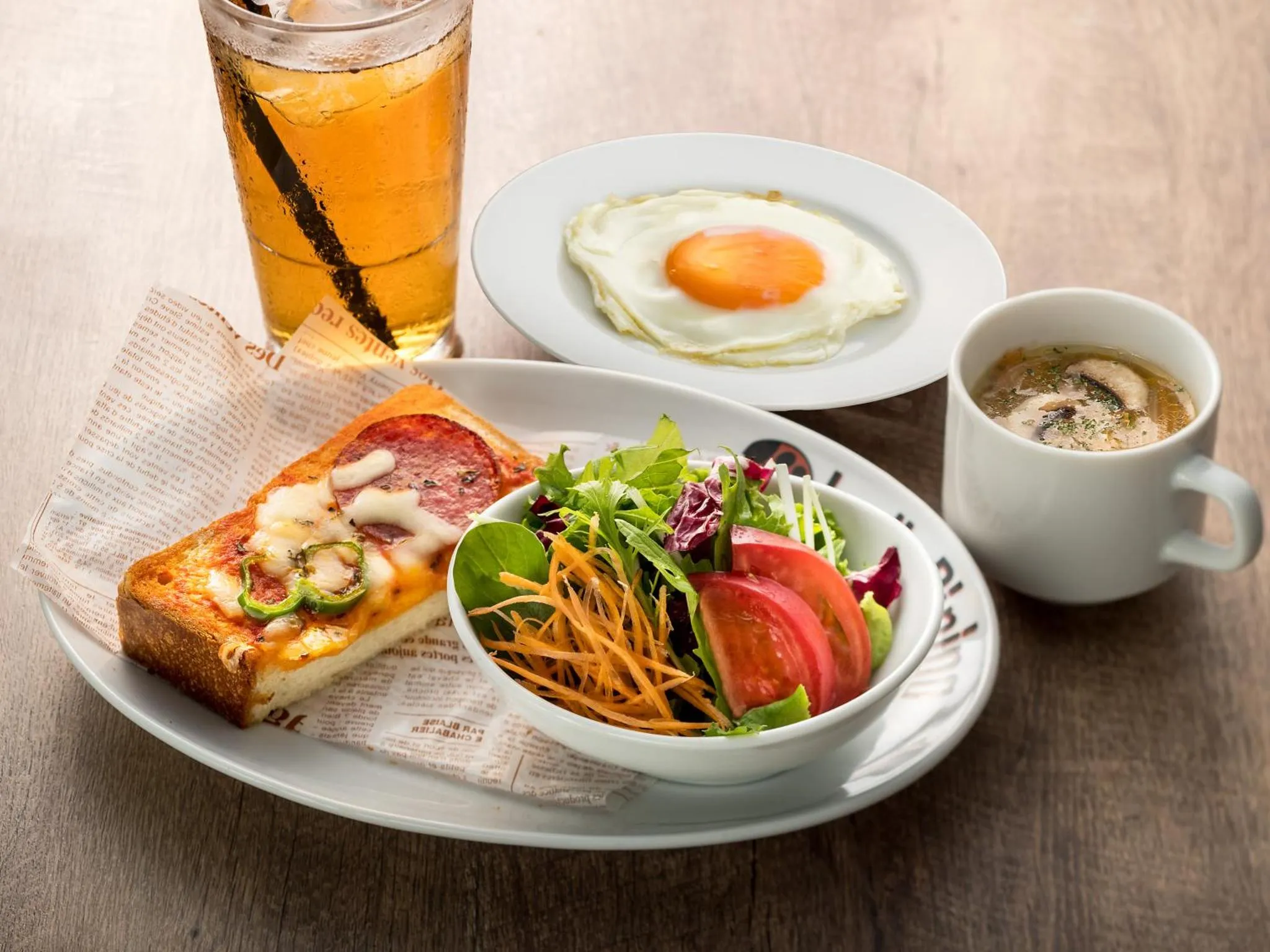 Assiette copieuse avec oeuf au plat, salade, sandwich et boisson.