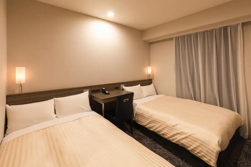 Une chambre avec deux lits simples et des lampes de chevet.