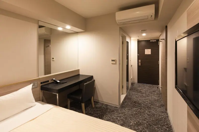 Une chambre d'hôtel lumineuse avec un lit et un bureau.