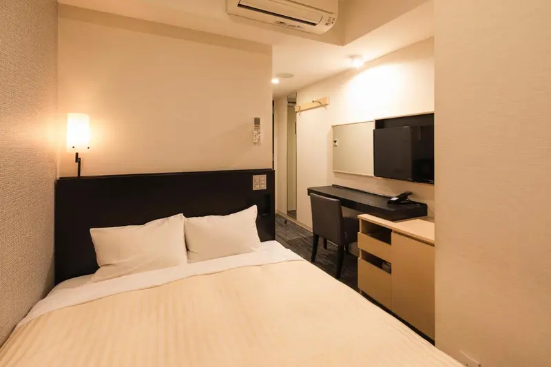Une chambre d'hôtel sobre avec un lit simple et un bureau.