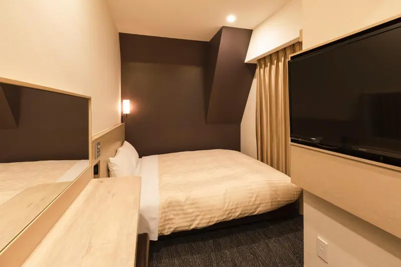 Une chambre avec deux lits simples et un téléviseur mural.