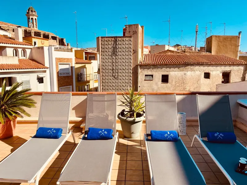 Terrasse ensoleillée avec chaises longues et plantes en pot.