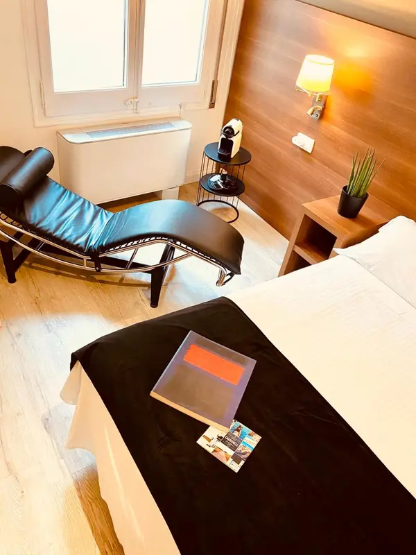 Une chambre lumineuse avec un lit et un fauteuil de relaxation.