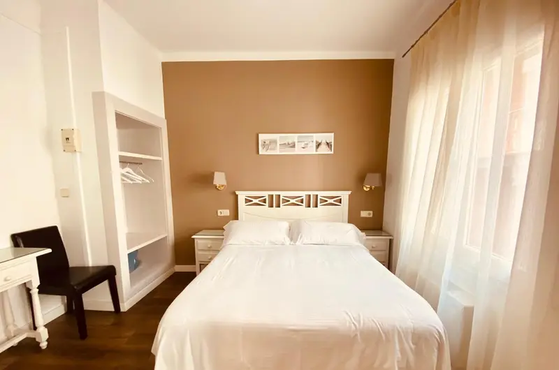 Une chambre lumineuse avec un lit blanc et un placard ouvert.