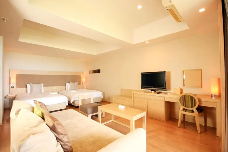 Une chambre lumineuse avec deux lits et un espace salon.