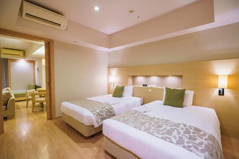 Chambre lumineuse avec deux lits simples et un espace détente.