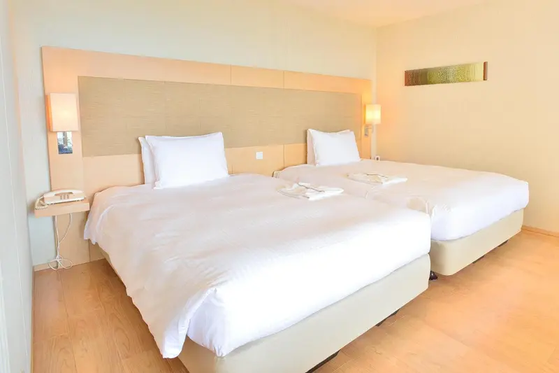 Une chambre lumineuse avec deux lits simples et une décoration sobre.