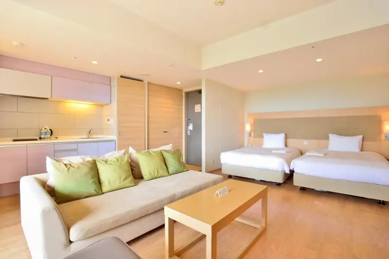 Espace de vie lumineux avec canapé, table basse et deux lits simples.