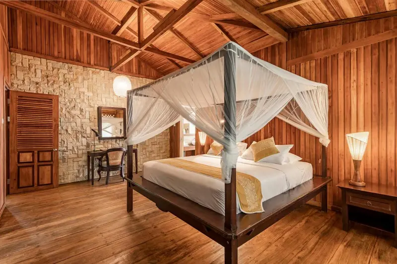 Une chambre lumineuse avec un grand lit à baldaquin et un sol en bois.