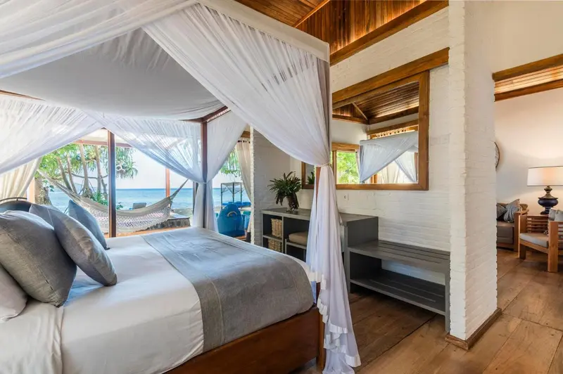 Une chambre lumineuse avec un lit à baldaquin et vue sur la mer.