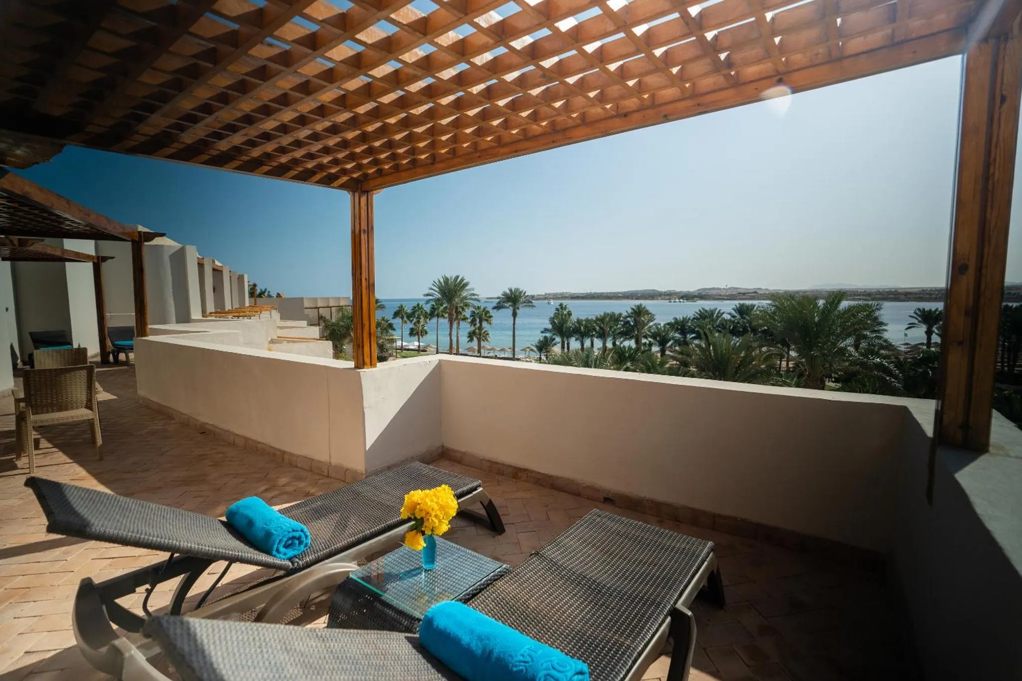 Terrasse ombragée avec transats et vue sur la mer.