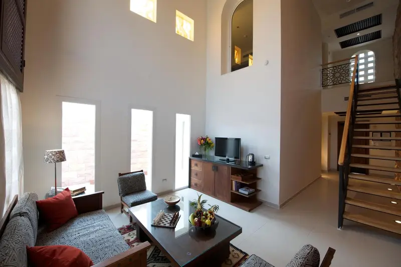 Un salon lumineux avec canapés, table basse et escalier menant à l'étage.