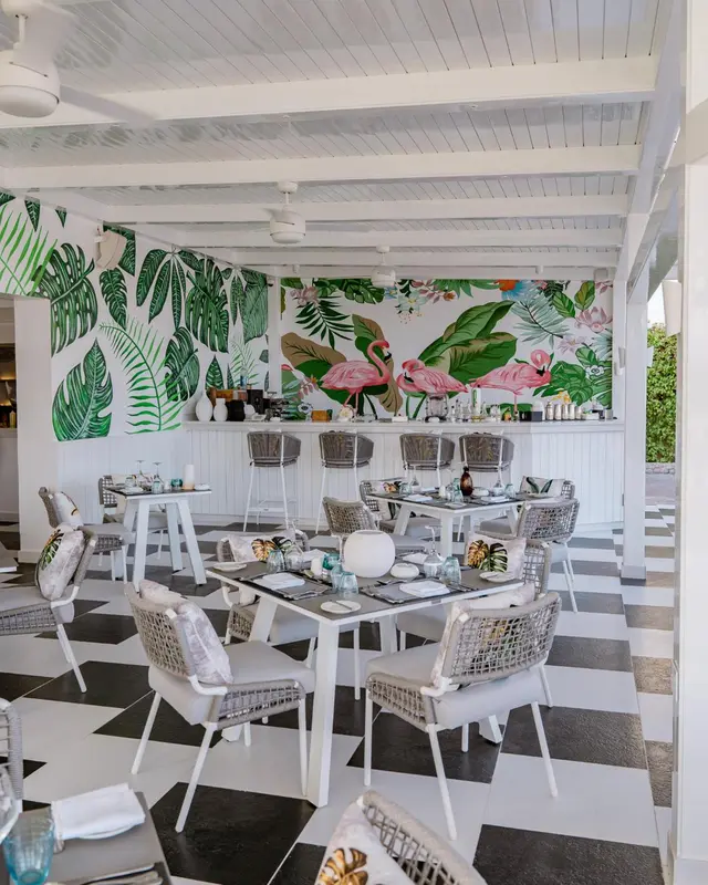 Une salle à manger lumineuse avec des tables et des chaises disposées sur un sol à carreaux noir et blanc.