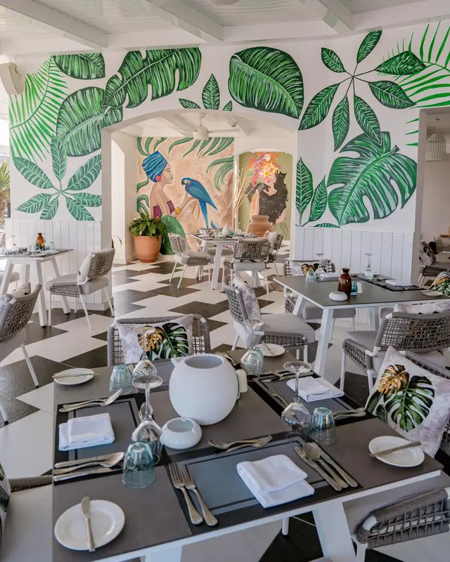 Une salle à manger lumineuse avec des tables dressées et une décoration tropicale.