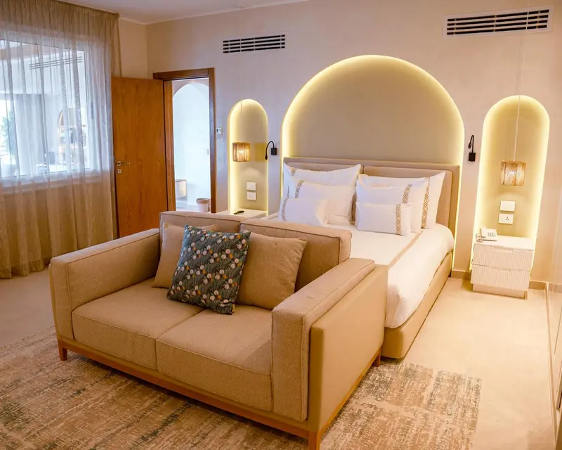 Une chambre lumineuse avec un grand lit et un canapé.