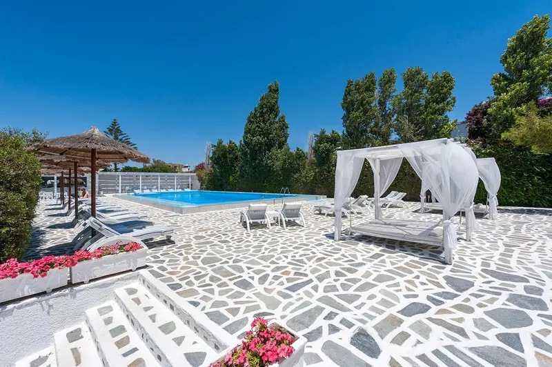 Transats blancs disposés autour d'une piscine rectangulaire en mosaïque.