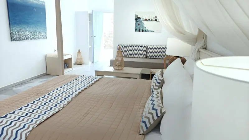 Une chambre lumineuse avec un grand lit et un coin salon.