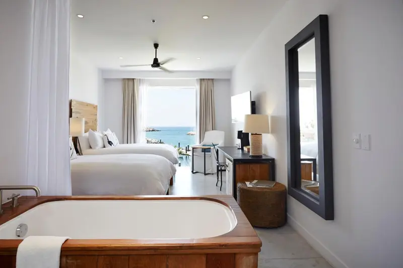 Une chambre lumineuse avec un grand lit et une baignoire.