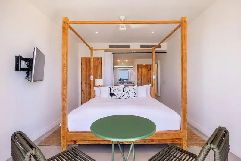Une chambre lumineuse avec un lit à baldaquin en bois et une petite table ronde.