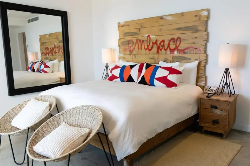 Une chambre lumineuse avec un grand lit et des fauteuils en osier.
