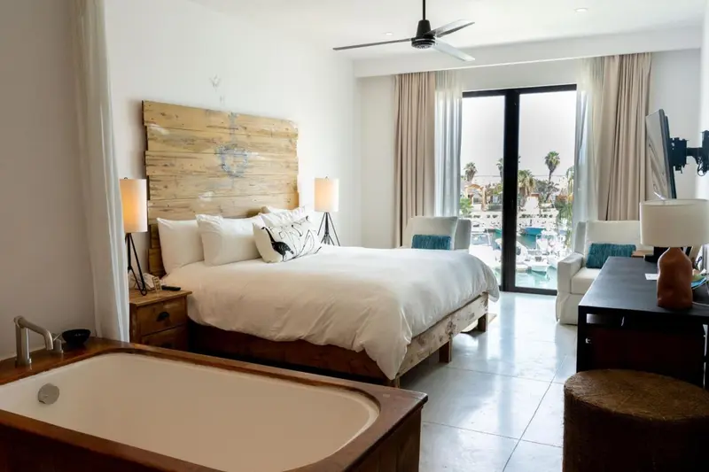 Chambre lumineuse avec un grand lit et une baignoire.