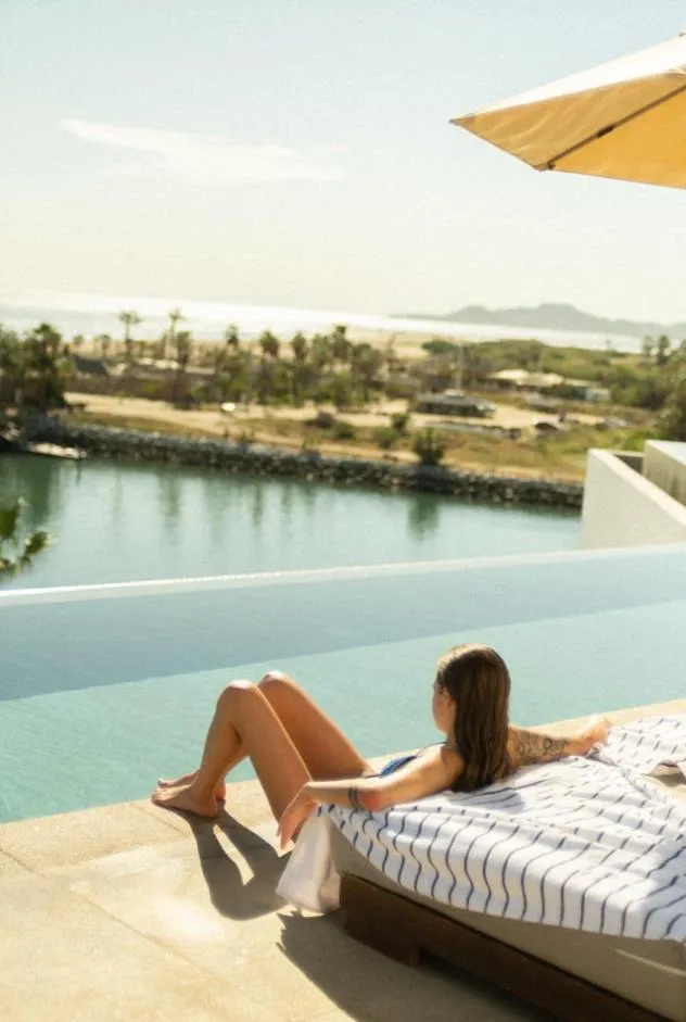 Une femme se détend au bord d'une piscine à débordement avec vue sur la mer.